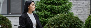 Tekerlekli sandalyedeki bir kadın sakince yeşilliklerin arasında oturuyor..