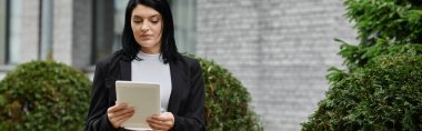 Tekerlekli sandalyedeki bir kadın açık havada tablet okuyor..