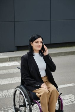 Tekerlekli sandalyedeki bir kadın yaya geçidinde otururken telefon eder..