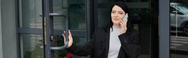 Takım elbiseli tekerlekli sandalye kullanıcısı telefonda konuşurken kapıyı açar
