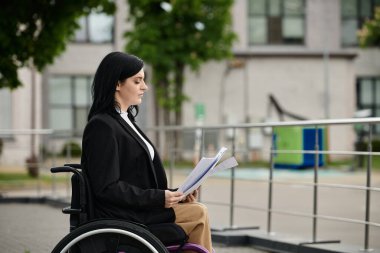 A woman in a wheelchair sits on a sidewalk, reading through papers. clipart