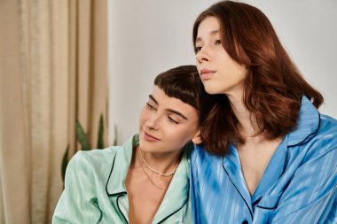 Genç bir lezbiyen çift pijamalarını giyer ve yakınlık anlarını paylaşır..