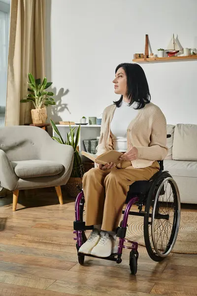 stock image A woman sits in a wheelchair, reading a book, and gazing out a window.