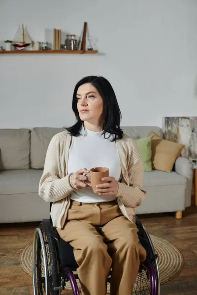 stock image A woman in a wheelchair sits in a living room, holding a cup of coffee and gazing thoughtfully.