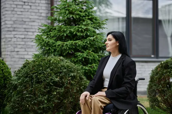 stock image A woman in a wheelchair sits thoughtfully in a garden.