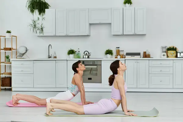 stock image A lesbian couple practicing yoga together in a modern kitchen.