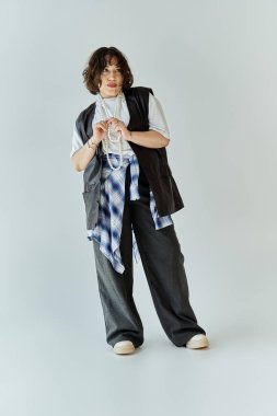 Beyaz bir arkaplanın önünde duran bir kadın duygusal bir ifadeyle yukarı bakıyor..