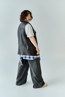 Deri yelek giymiş bir kadın, kendine güveni tam bir şekilde arkasını kolluyor..