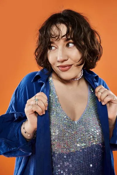 stock image A woman in a blue shirt adjusts her sparkly top.