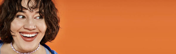 Женщина в ярких лучах одежды с радостью на ярком оранжевом фоне.