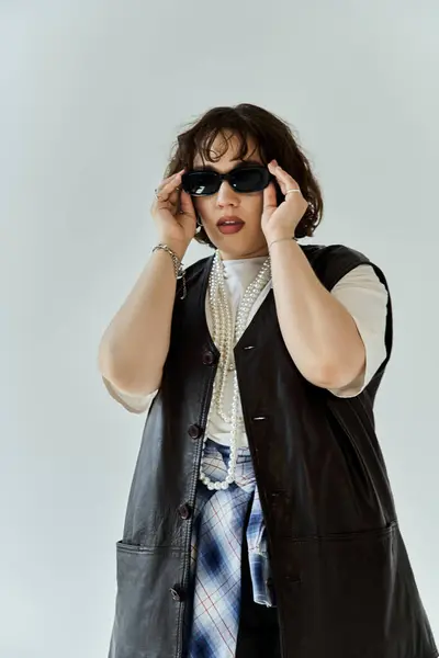 stock image A woman wearing a leather vest and sunglasses looks confidently at the camera.