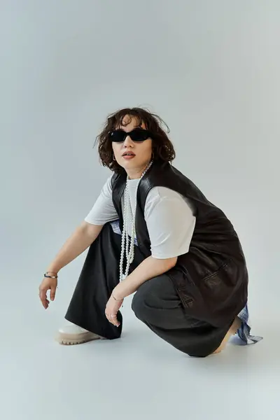 stock image A woman in a leather vest and sunglasses poses against a white backdrop.