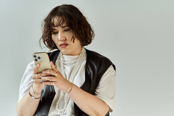 A woman in a vibrant vest looks intently at her phone.