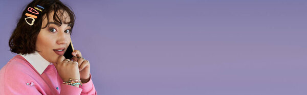 Женщина в розовой одежде говорит по телефону, ее лицо светится от радости.