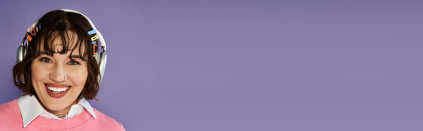 Молодая женщина в ярком наряде счастливо улыбается, надевая наушники..