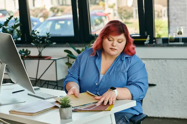 stock image A plus size businesswoman sits at a desk examining a color palette.