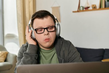 Down sendromlu genç bir adam rahatça otururken kulaklıkla müzik dinliyor..