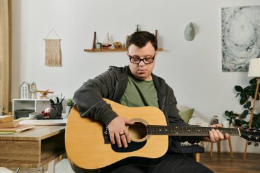 Down sendromlu genç bir adam evde dinlenirken gitar çalıyor..