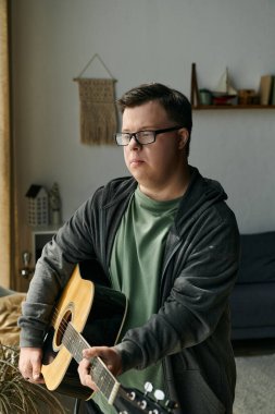 Down sendromlu genç bir adam gitarını evde tıngırdatırken müziği kucaklıyor..
