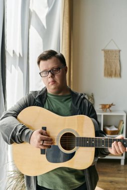 Down sendromlu genç bir adam gitar çalıyor, müziğe olan aşkını içeride kucaklıyor..