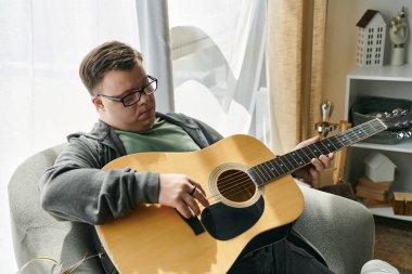 Down sendromlu bir adam rahat bir evde gitar tıngırdatmaktan hoşlanır..
