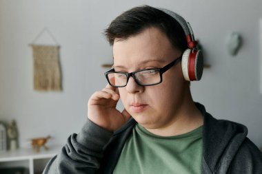 Down sendromlu genç adam evde dinlenirken dikkatle müzik dinliyor..