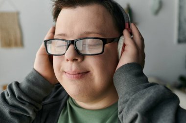 Down sendromlu genç bir adam evde dinlenirken neşeyle müzik dinliyor..