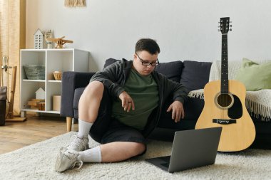 Down sendromlu genç bir adam evinde dinlenirken dizüstü bilgisayara dalmış..