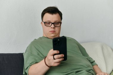 Down sendromlu bir adam telefonunu kontrol ederken kanepede dinleniyor..
