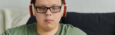 Down sendromlu genç bir adam evde müzik dinlemekten hoşlanıyor, odaklanmış ve memnun..