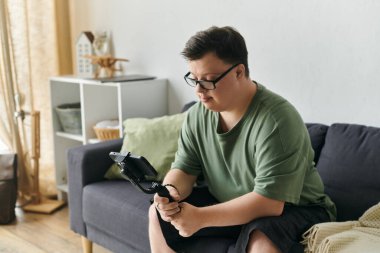 A young man with Down syndrome enjoys a creative moment at home, focusing intently on his task. clipart