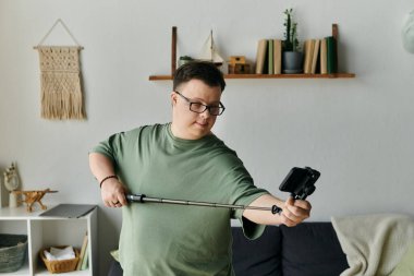 Down sendromlu genç bir adam keyifle oturma odasında selfie çekiyor..