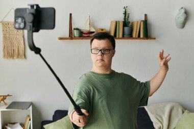 Down sendromlu bir adam oturma odasında mutlu mesut selfie çekiyor..