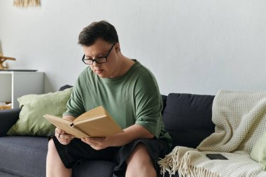 Down sendromlu nişanlı bir adam rahat bir koltukta kitap okumayı sever..