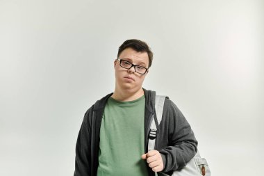 A young man with Down syndrome stands thoughtfully, ready for a new journey.