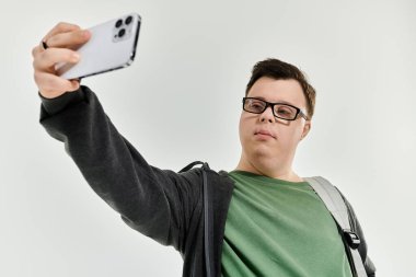 Down sendromlu genç bir adam evde selfie çekerken kendinden emin bir şekilde gülümsüyor..