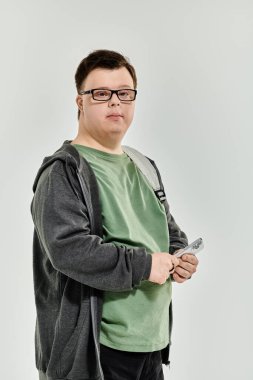 Down sendromlu genç bir adam elinde uzaktan kumandayla evde vakit geçirmekten zevk alıyor..