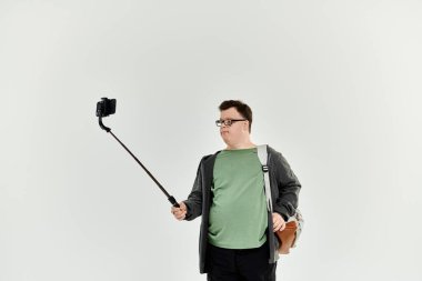 Down sendromlu genç bir adam evinde selfie çubuğuyla bir anı neşeyle yakalıyor..
