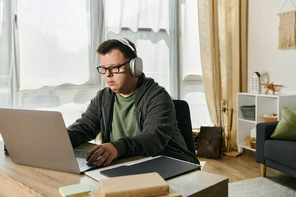 stock image A man with Down syndrome studies intently on his laptop at home.