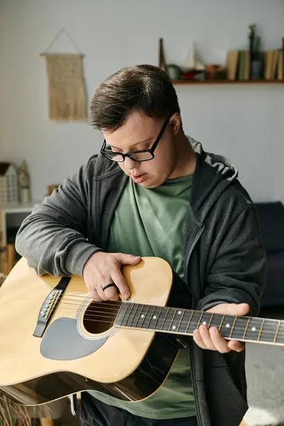 stock image He strums a guitar, enjoying music in a warm and inviting space.