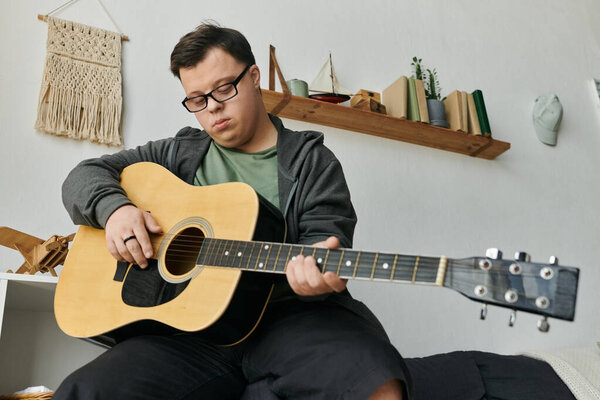 A young man with Down syndrome enjoys playing guitar in his cozy living space.