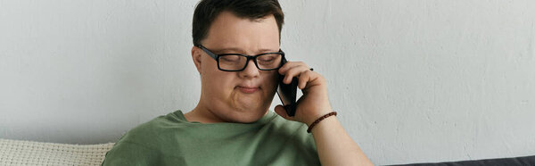 Мужчина с синдромом Дауна разговаривает по телефону, улыбаясь в своем удобном жилом пространстве.