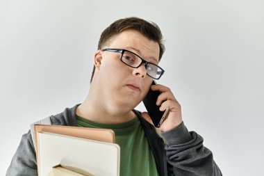Down sendromlu genç bir adam dosyaları tutarken telefonla konuşuyor..