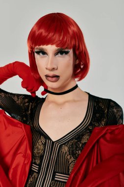 Çekici, genç bir travesti cesur makyajı ve canlı kıyafetleriyle poz veriyor..