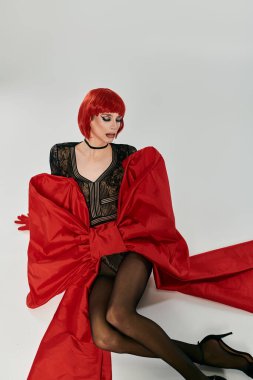 Çekici travesti, canlı kırmızı elbisesiyle kendine güvenini sergiliyor..