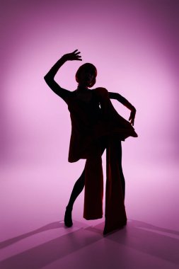 Çarpıcı bir travesti canlı renklerle siluetli hareketli bir poz verir..
