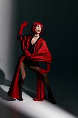 Genç bir travesti çarpıcı kırmızı elbisesiyle dramatik bir şekilde poz verir..