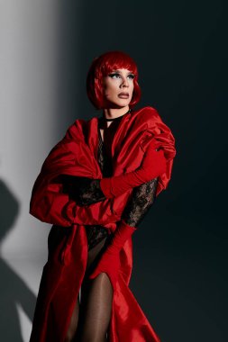 Çarpıcı genç bir travesti kendine güvenen kırmızı elbisesiyle poz verir..