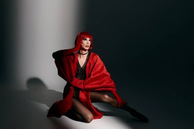 Çekici bir travesti canlı kırmızı bir poz verirken kendine güvenir..