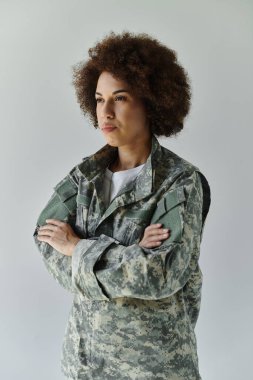 Kararlı genç bir Afro-Amerikan askeri kadın gururla kamuflaj kıyafetiyle ayakta duruyor..